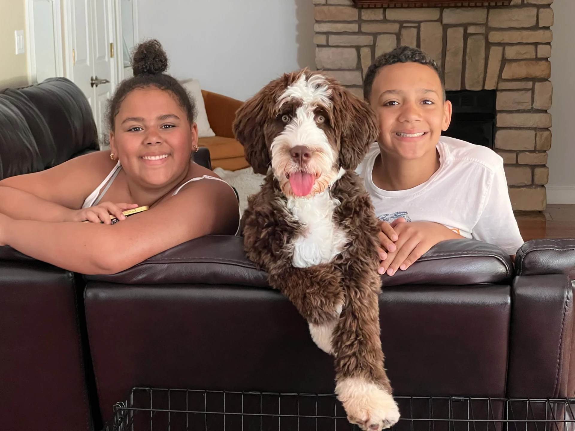 Two children snuggled on a couch with their dog between them